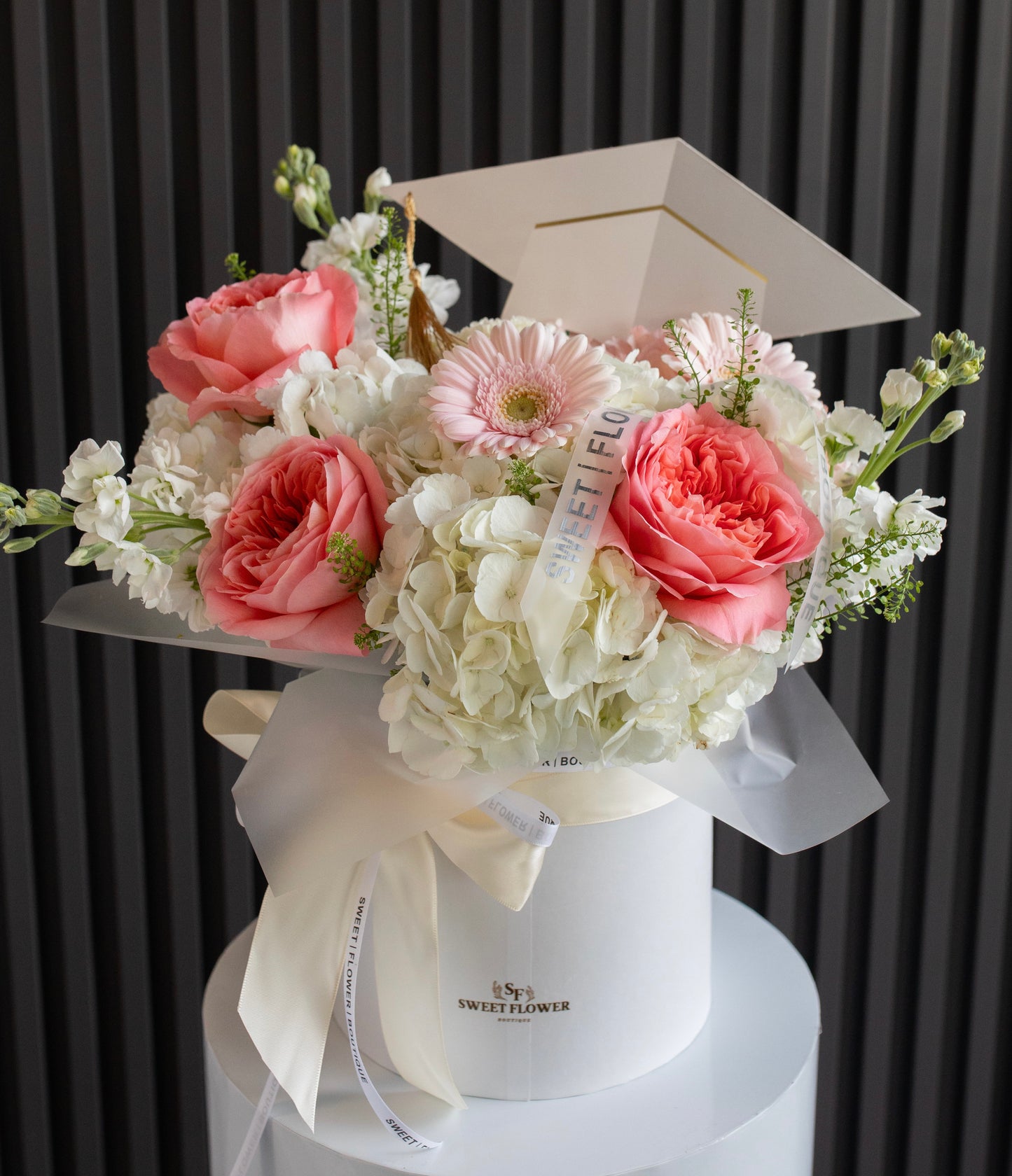 Graduation floral arrangement in white hat box with graduation cap