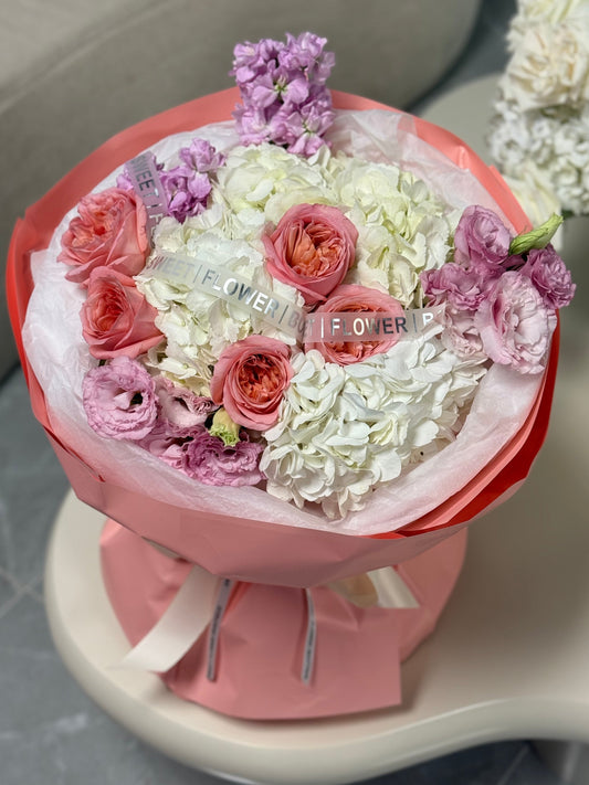 Bouquet of flowers in a pink container with 'Forever Flower' text on a gray surface.
