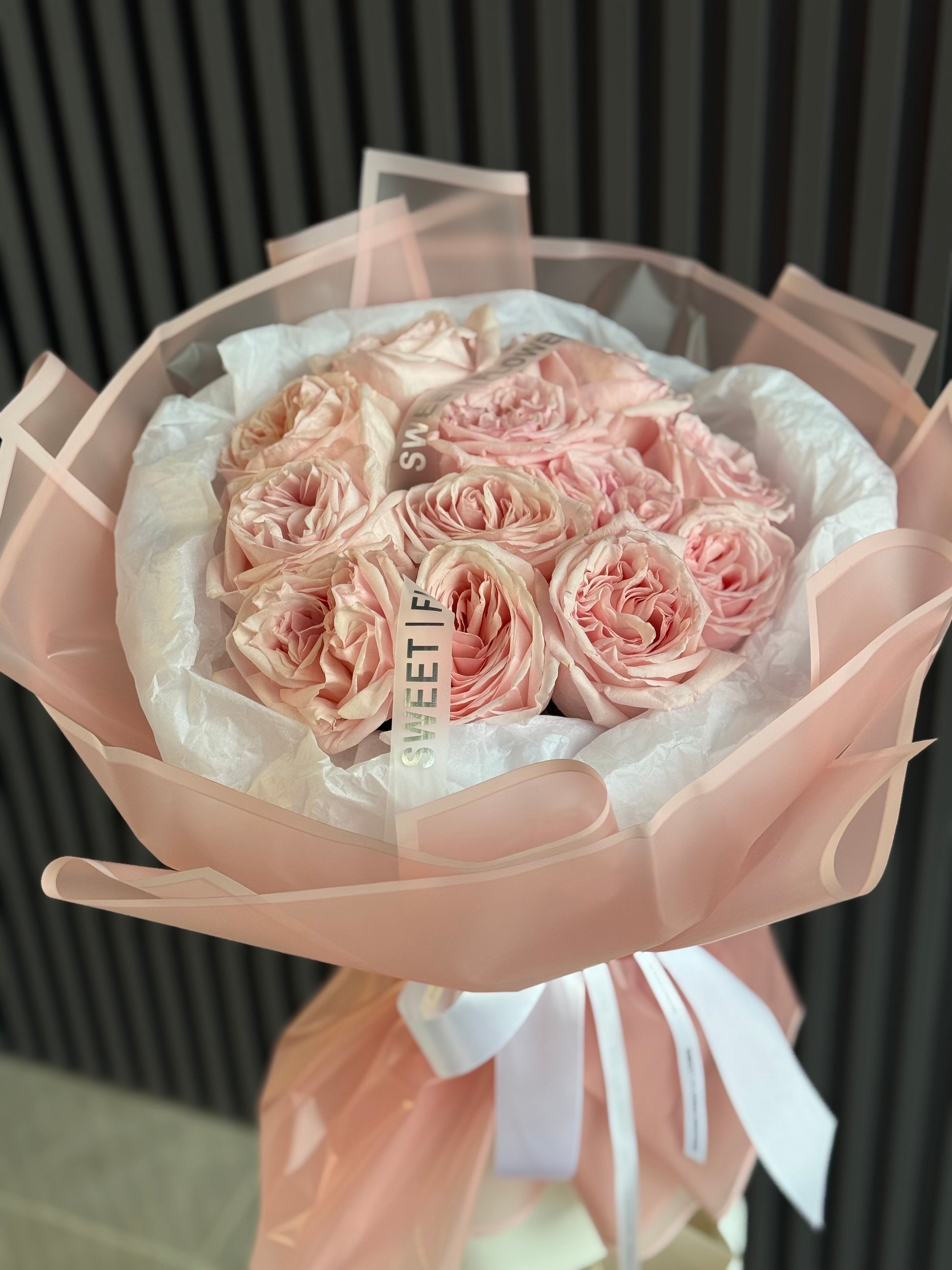 Bouquet of pink roses wrapped in white paper with a black background