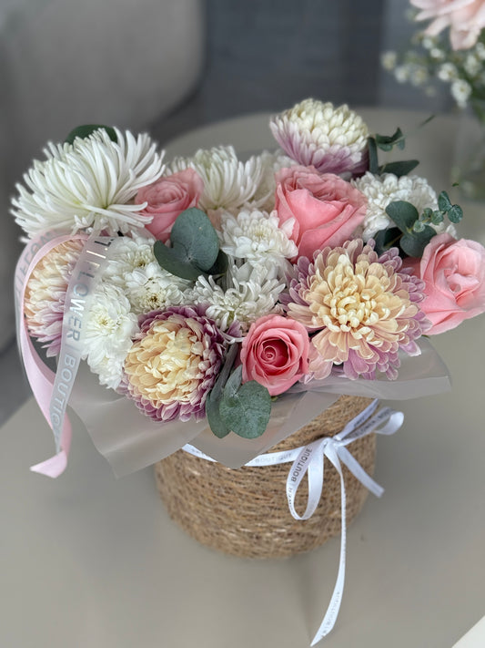 Blush and cream flower basket with roses, chrysanthemums, and eucalyptus in a woven base, designed for same-day delivery.
