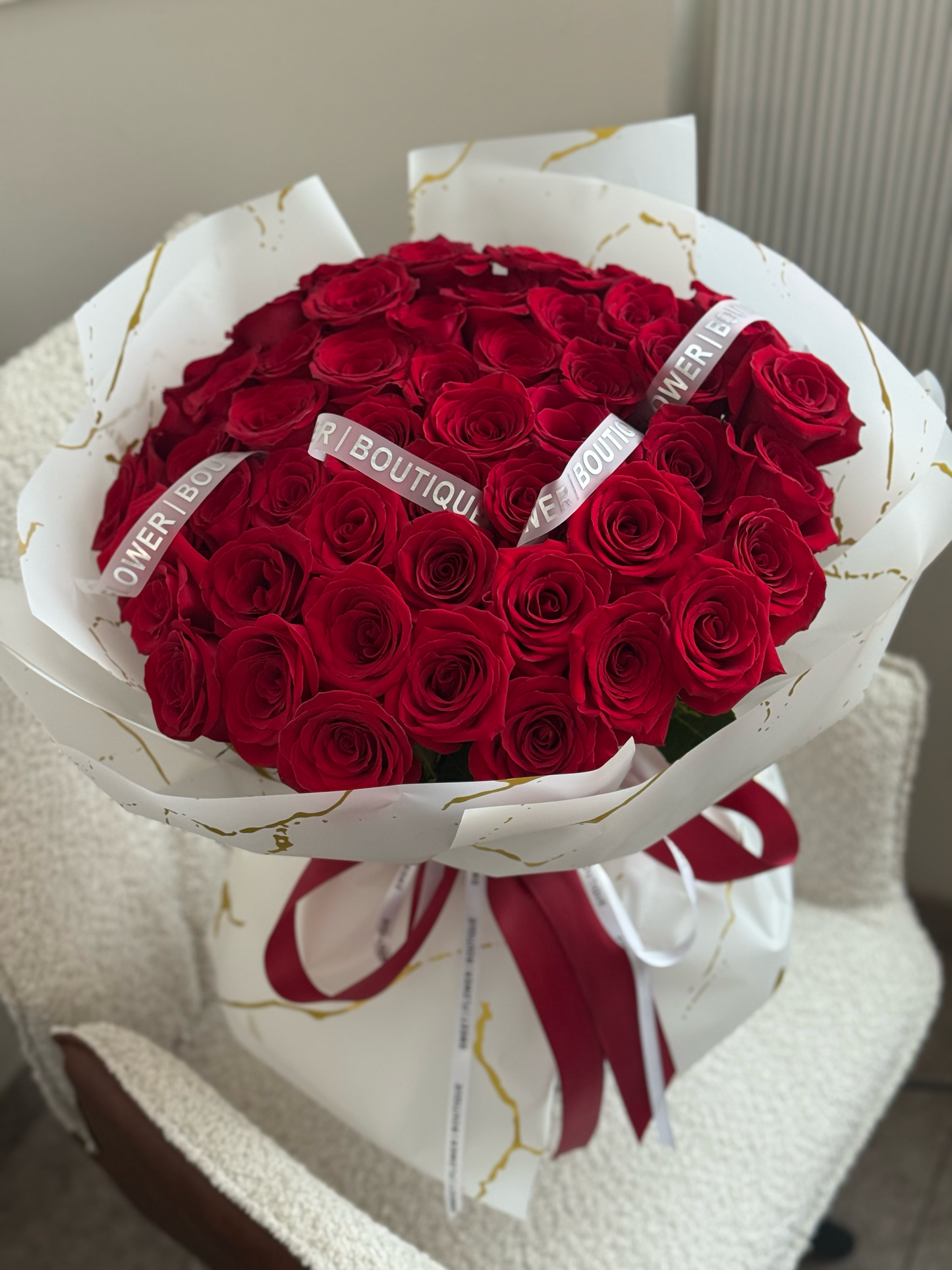 Bouquet of red roses with a white ribbon on a light background