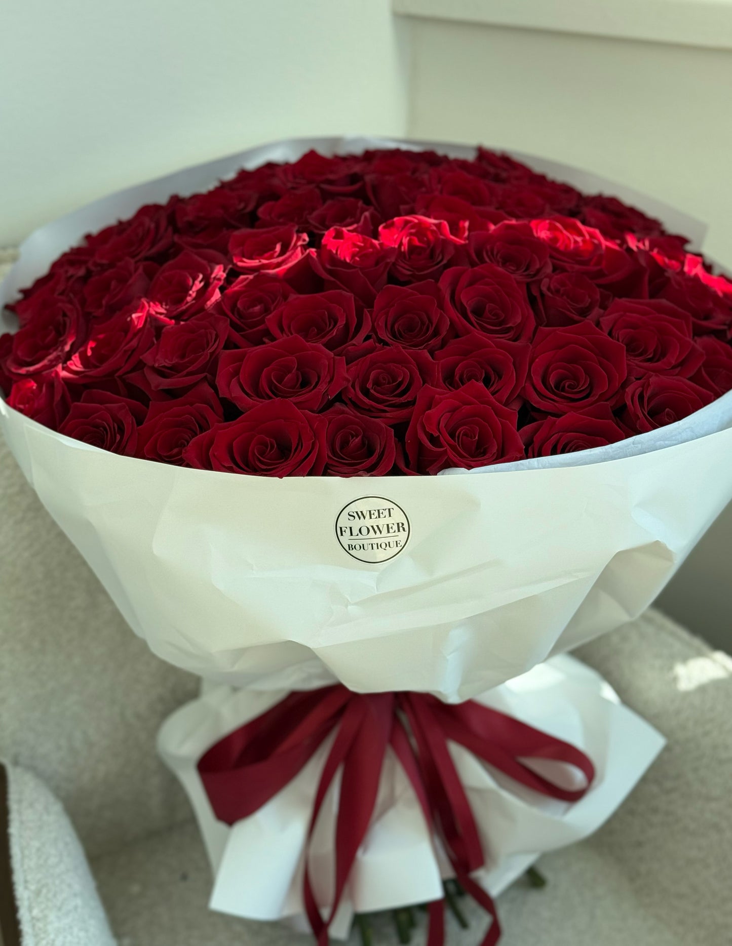 75 red roses bouquet wrapped in white paper with red ribbon by Sweet Flower Boutique