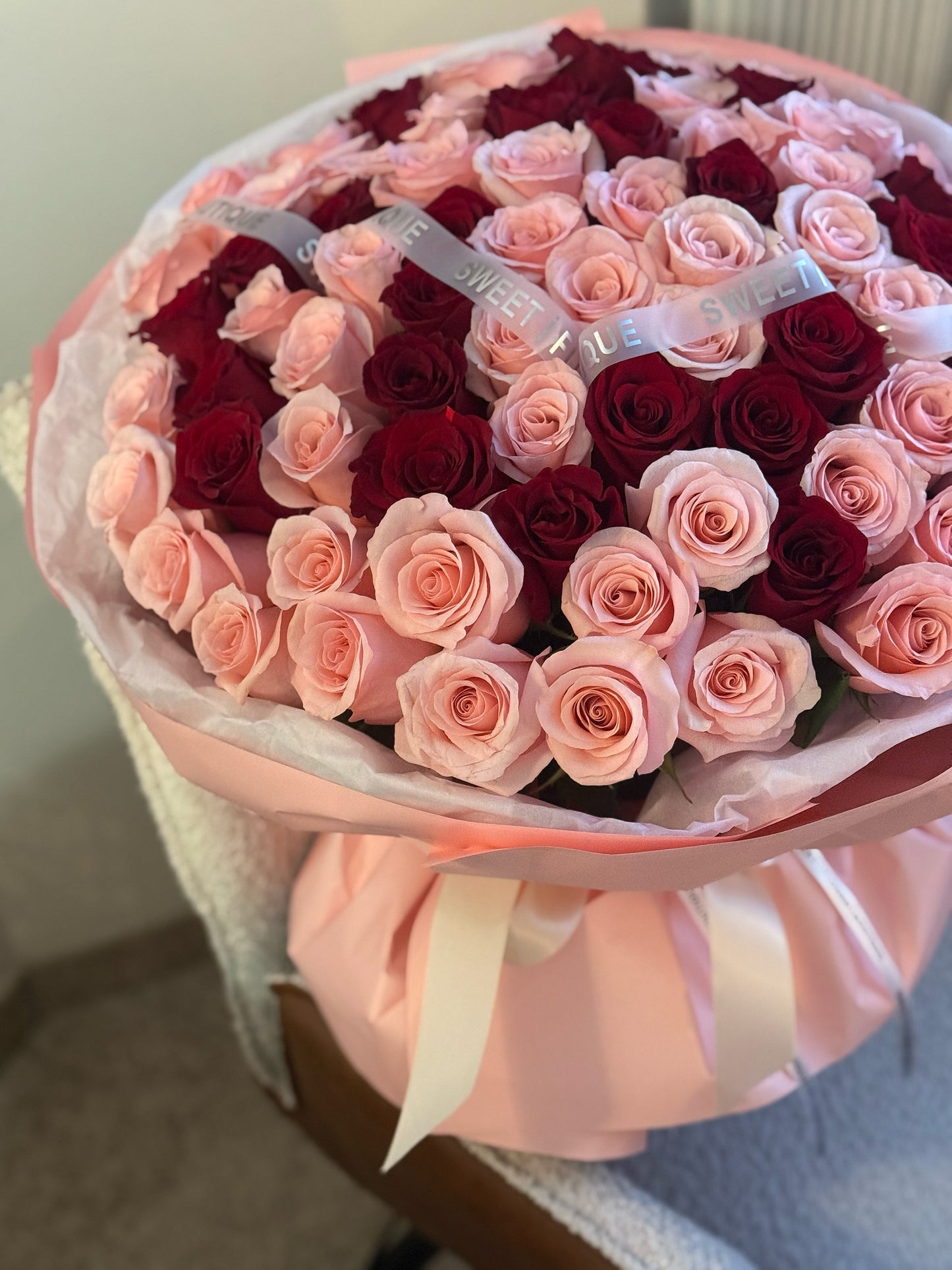 Pink and red roses bouquet wrapped in soft pink paper by Sweet Flower Boutique