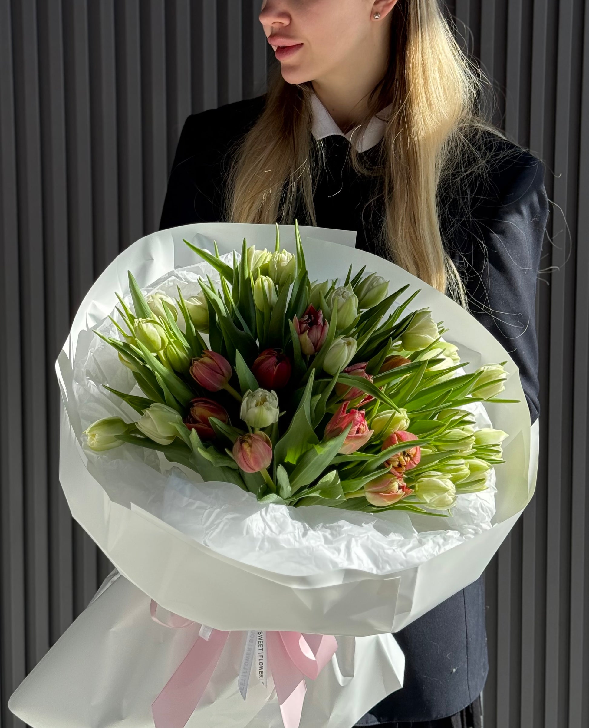 Person holding a bouquet of tulips against a neutral background