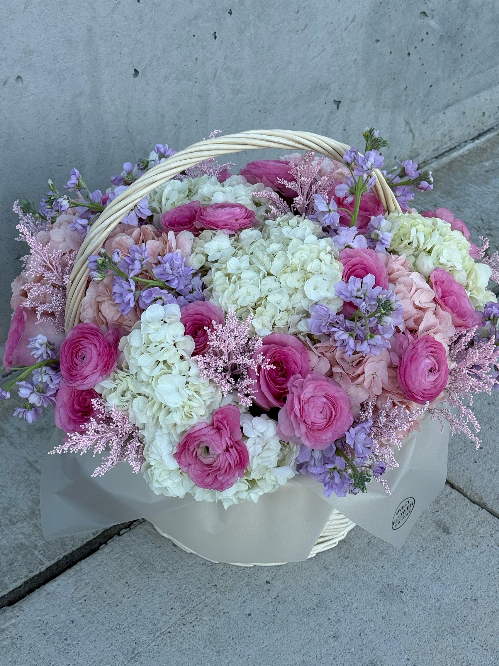 Basket of pink and white flowers on a concrete surface