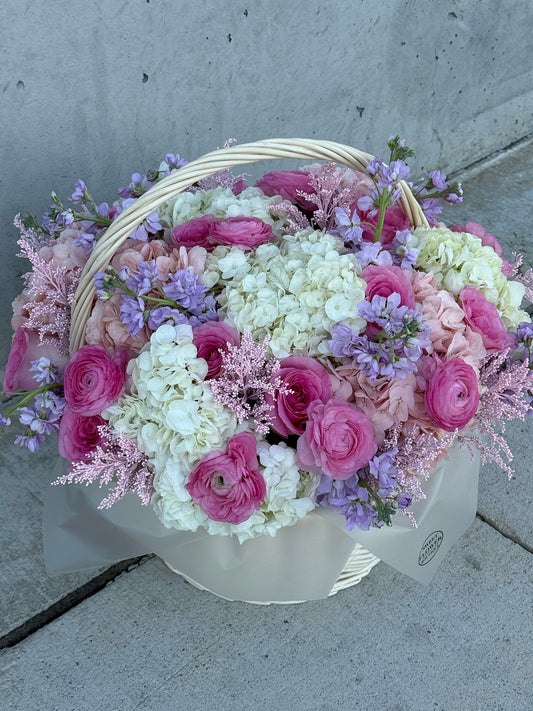 Basket of pink and white flowers on a concrete surface