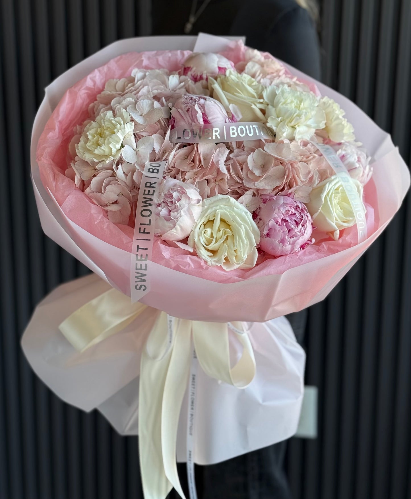 Romantic pink peony and hydrangea bouquet wrapped in premium paper