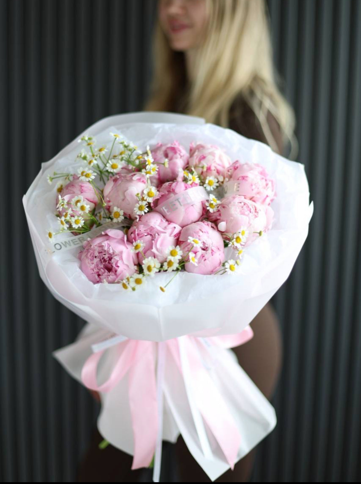 Fresh pink peony and chamomile bouquet wrapped in premium paper