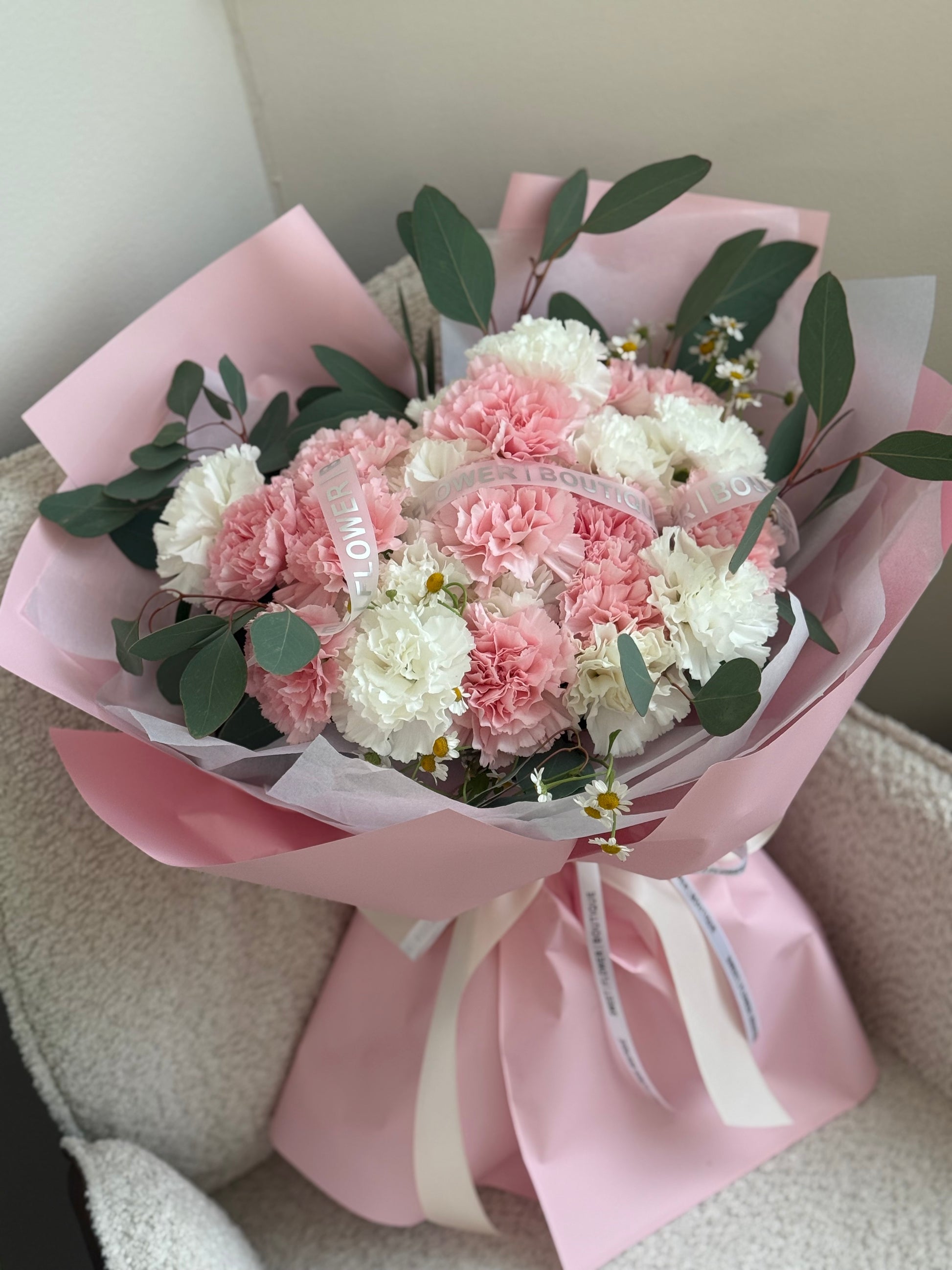 Pink and white carnations bouquet wrapped with pink paper wrap 