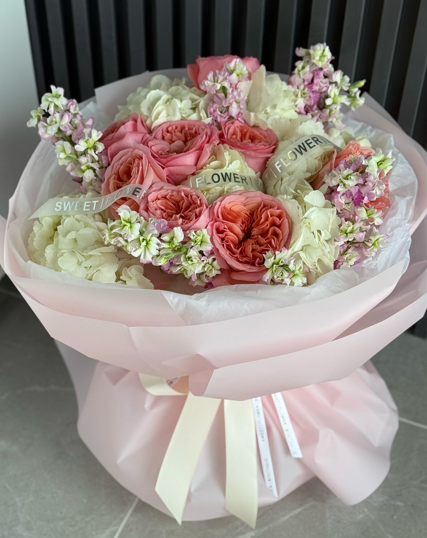Bouquet of pink and white flowers with a pink wrap on a light surface.