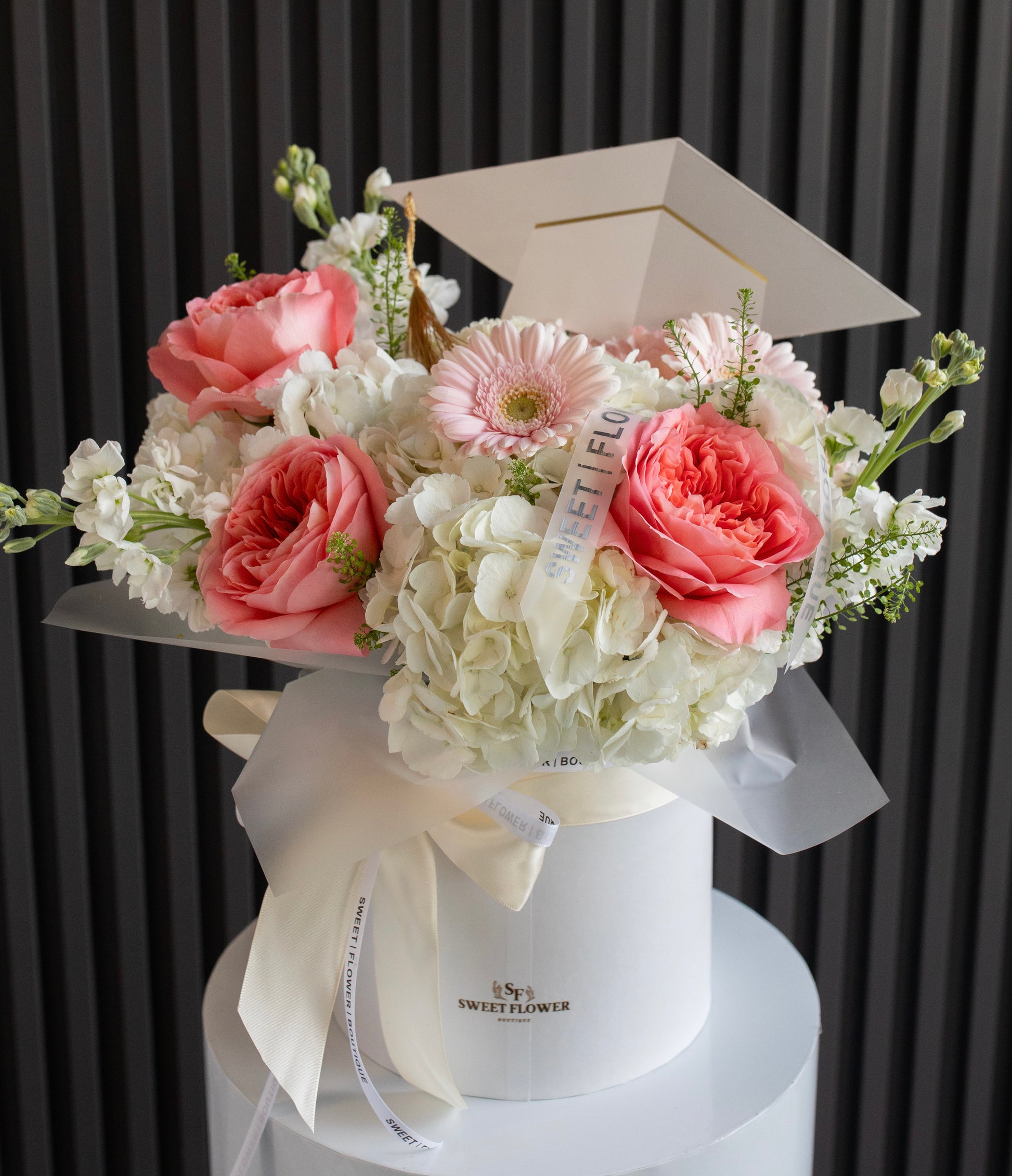 Graduation floral arrangement in white hat box with graduation cap