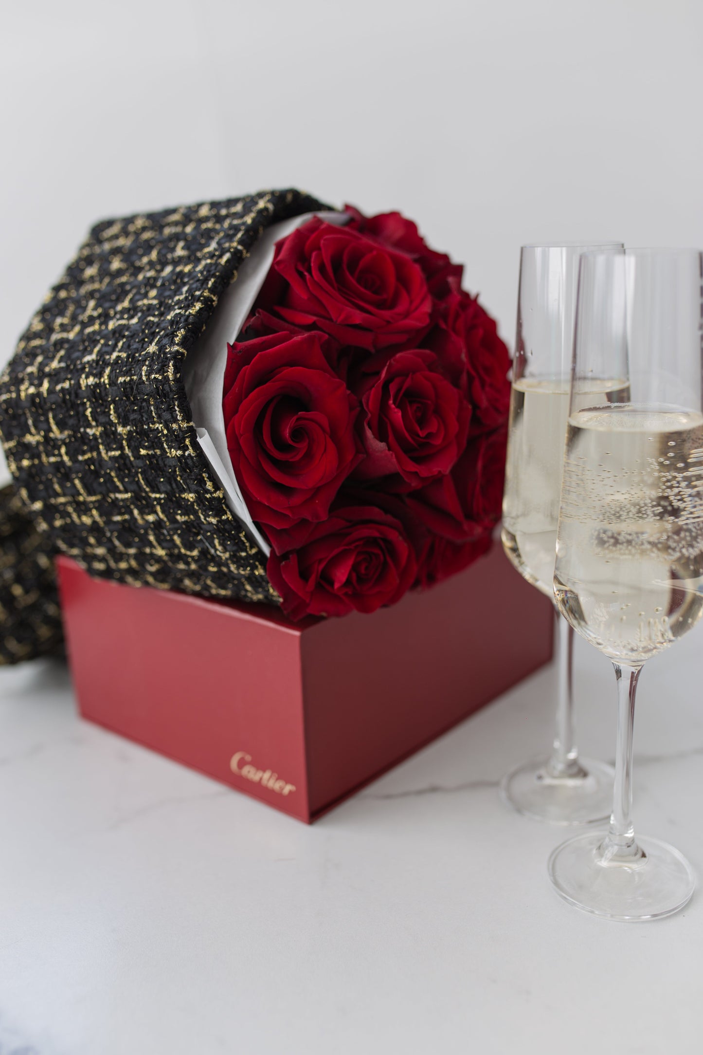 Close-up of twelve red roses arranged in black tweed wrap with white ribbon