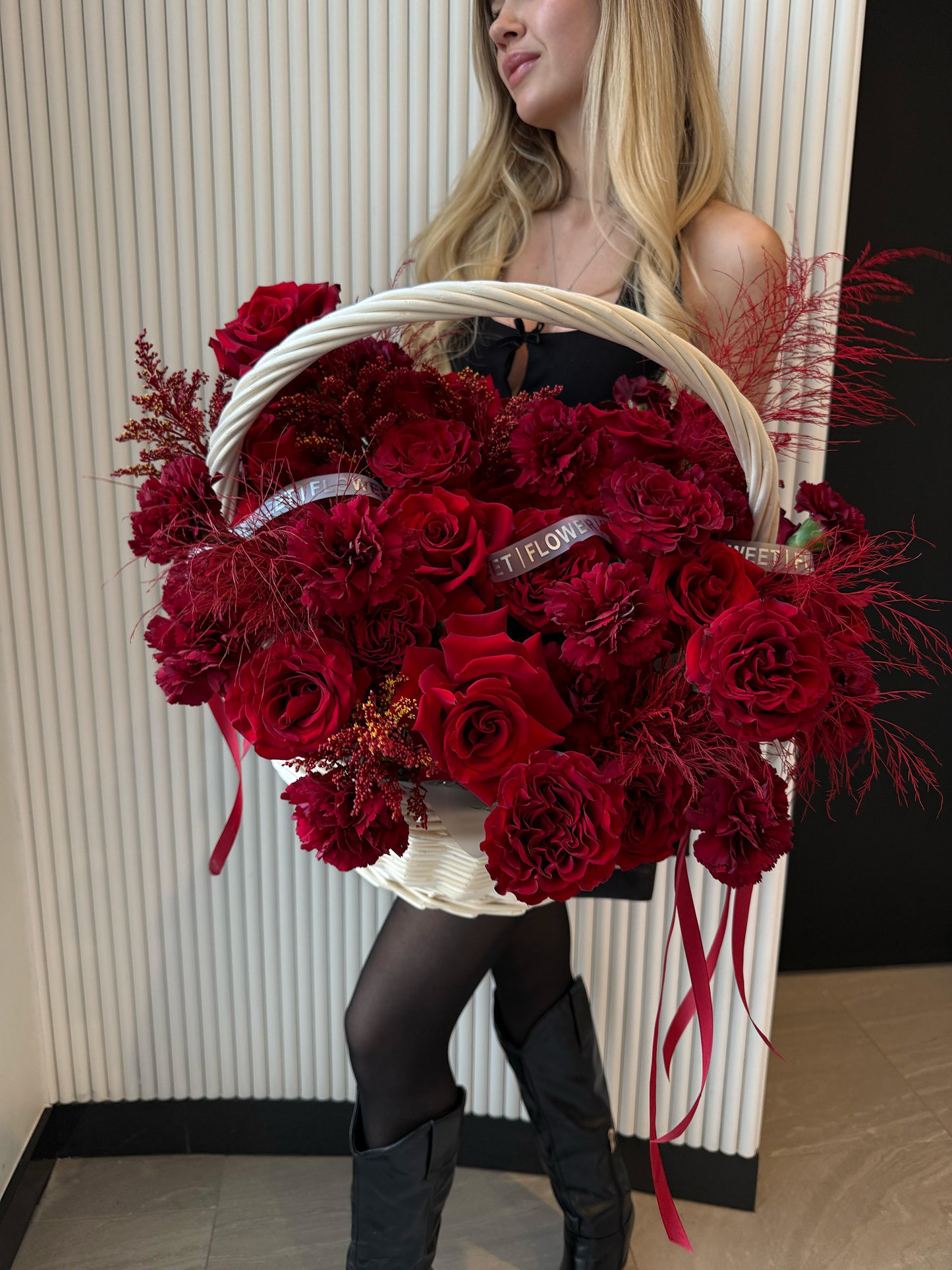 Woman holding a red roses and carnations basket made from natural vines