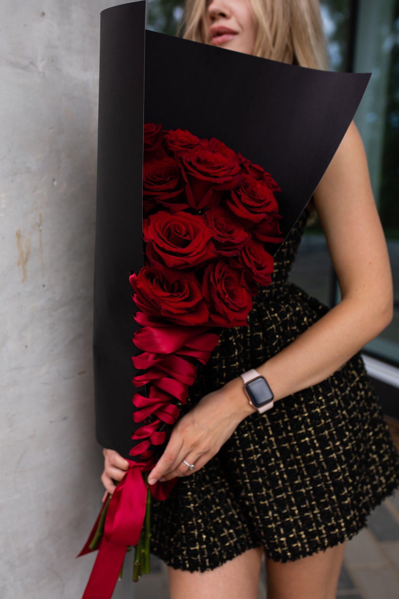 Close-up of twenty red roses arranged in black wrap with red satin ribbon
