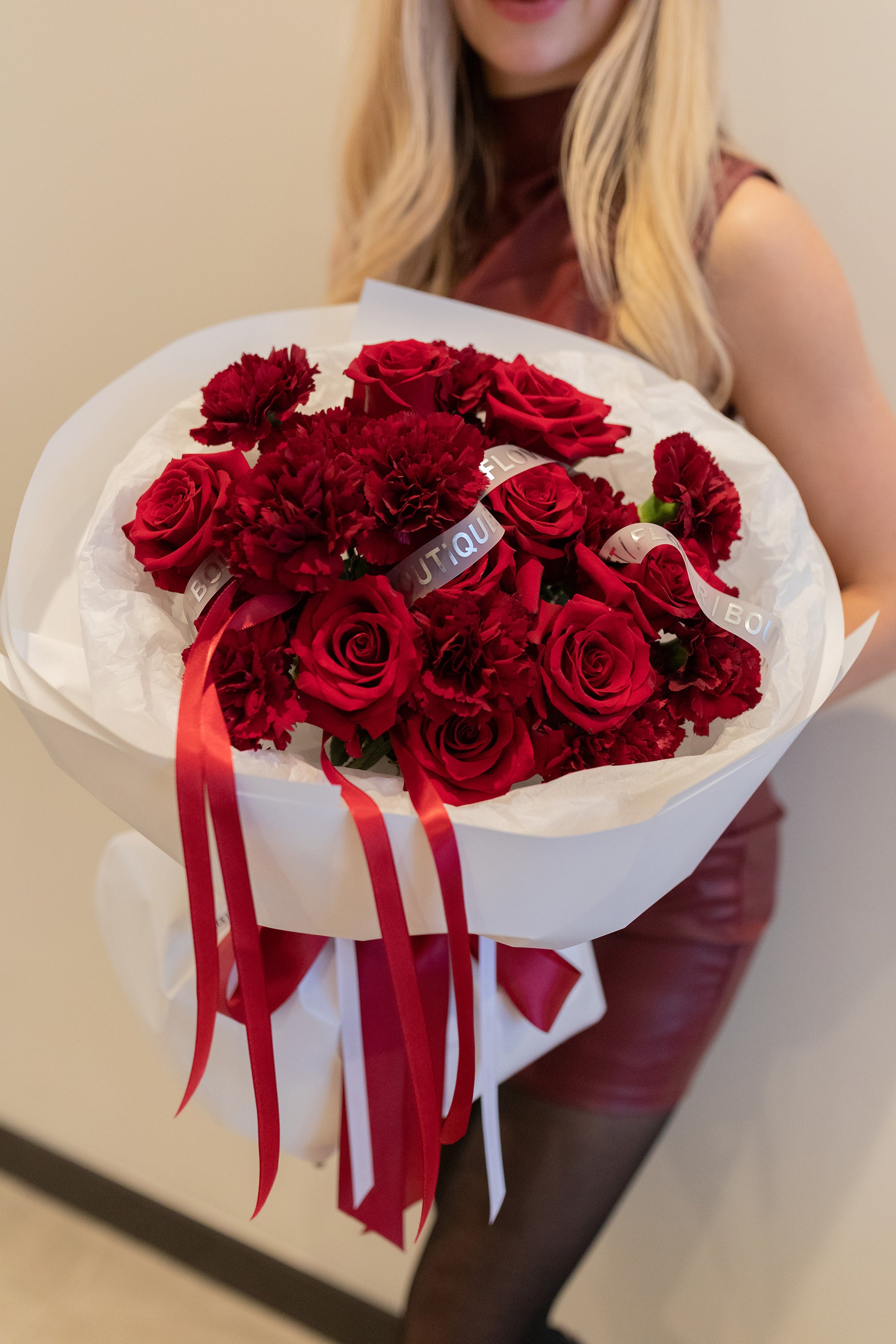 Woman holding red roses and carnations bouquet, elegant romantic flowers